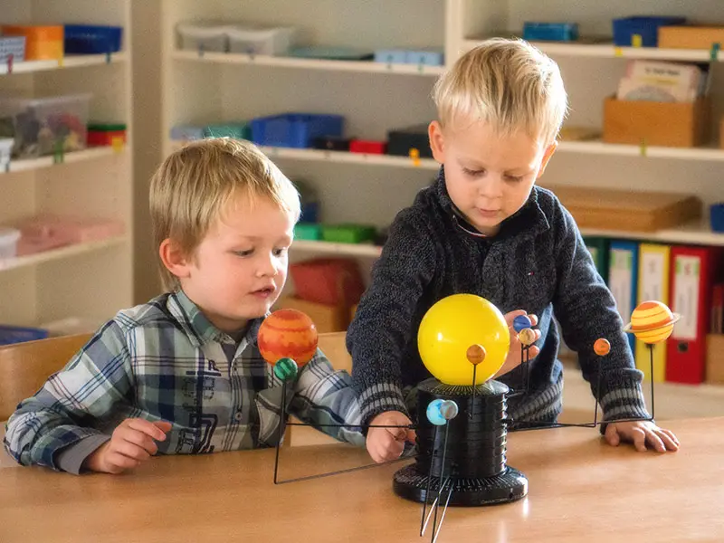 Zwei Kinder erkunden gemeinsam ein Modell des Sonnensystems