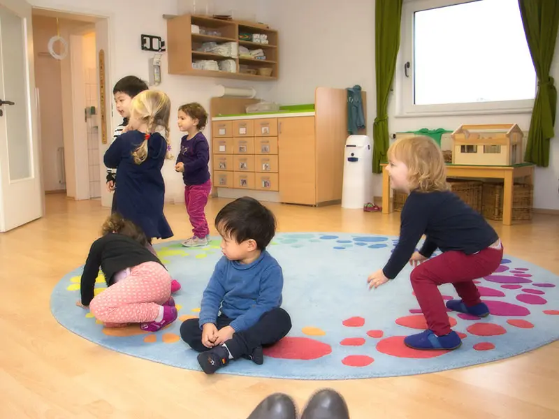 Kindergruppe bewegt sich gemeinsam auf dem Teppich im Gruppenraum
