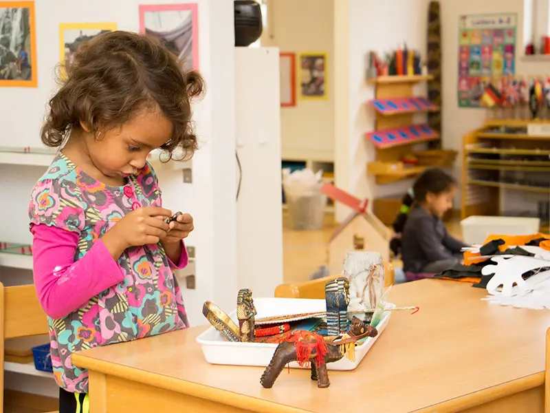 Kind arbeitet selbstständig mit Montessori-Materialien an einem Tisch